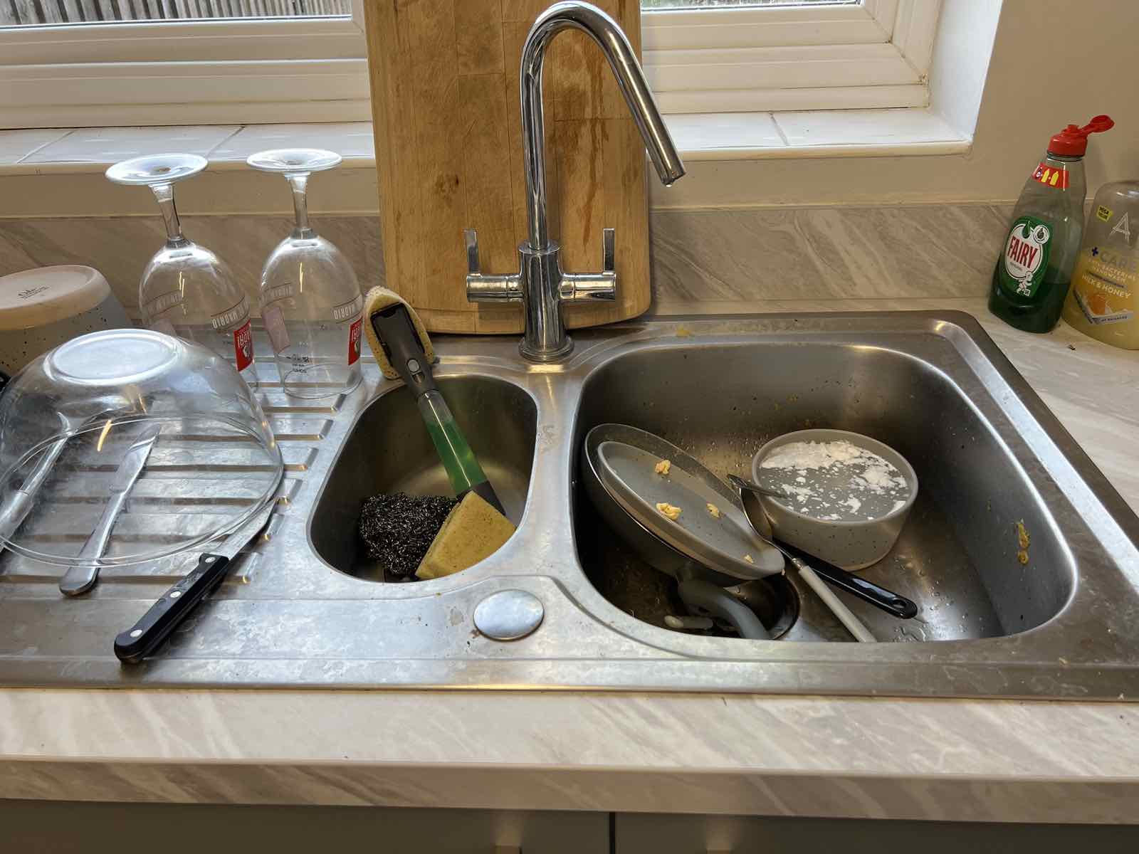 Kitchen sink piled with dishes before cleaning